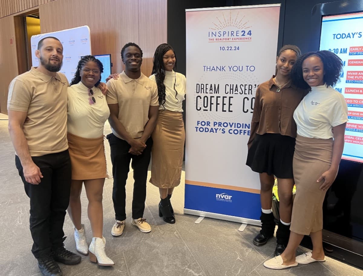 Leo and the Dream Chasers Coffee team at the NVAR INSPIRE24 Realtor Experience event in front of a thank-you banner